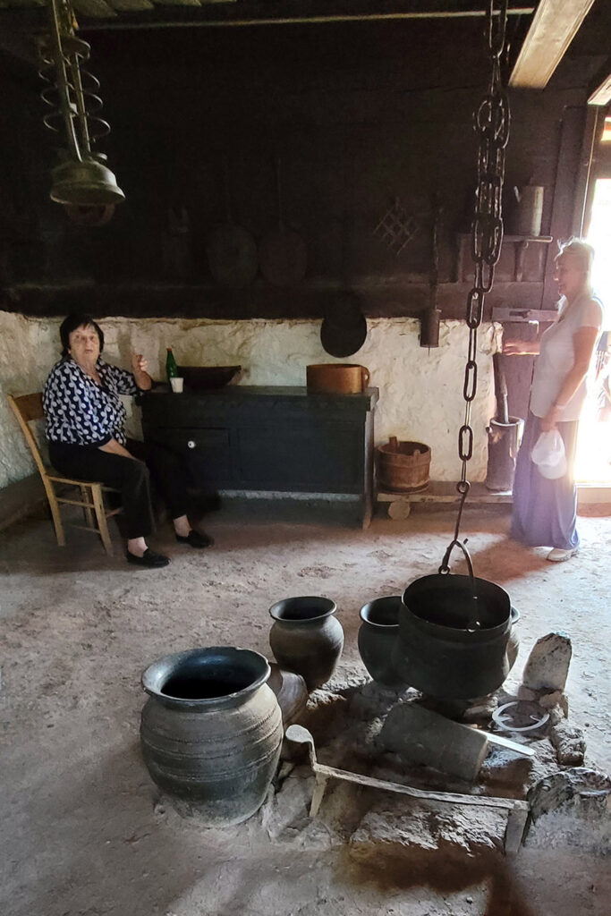 Historisch eingerichteter Wohnraum mit Holzmöbeln und Feuerstelle in einem Blockhaus in Sirogojno – City-Check Zlatibor, FemNews.de Traditionell eingerichteter Wohnraum in einem Haus des Freilichtmuseums Sirogojno